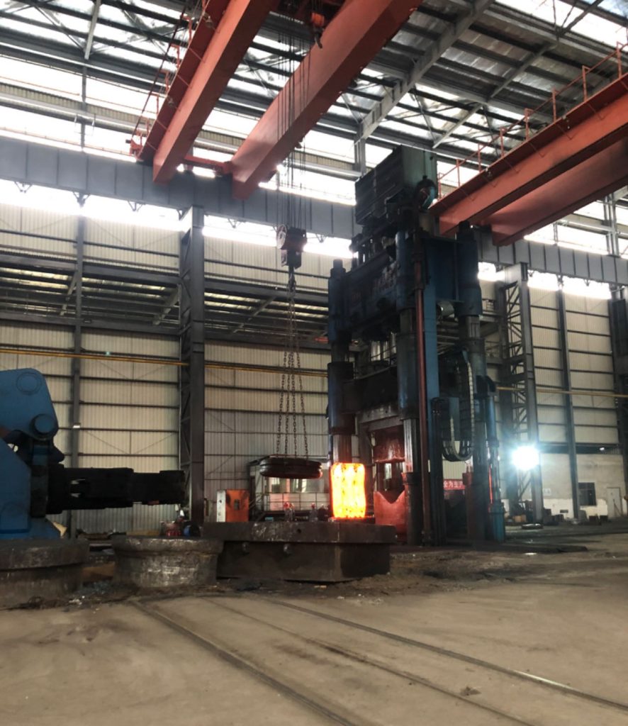 The colossal 10,000-ton hydraulic forging press, its towering frame dominating the industrial facility.