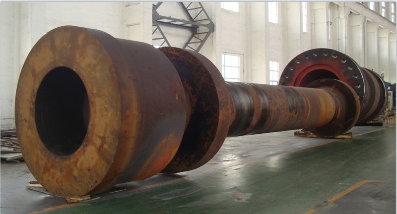 A large, forged steel support roller shaft for a cement plant rotary kiln, precision-machined and ready for assembly with the roller.
