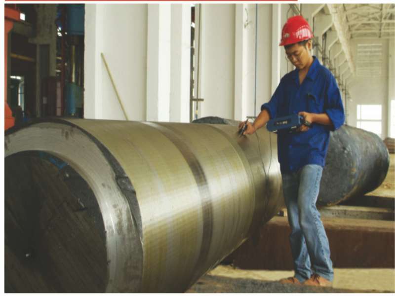 Technician performing ultrasonic testing (UT), a non-destructive test (NDT), on an isostatic press core barrel to detect internal flaws.