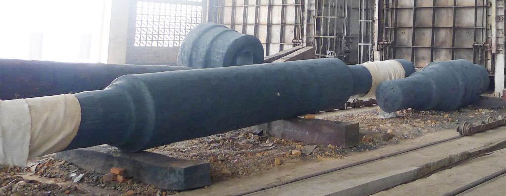 A massive 10-meter long, 1.5-meter diameter forged steel shaft undergoing rough machining on a heavy-duty CNC lathe in a factory setting.