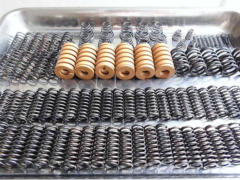 A collection of custom-engineered, heavy-duty springs designed for isostatic presses, showing various sizes and coil types.